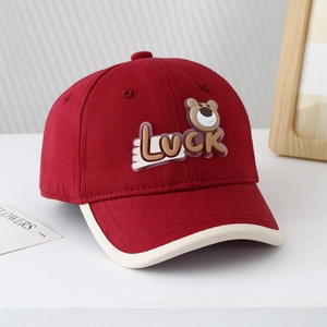 Détail d'une casquette bébé rouge avec écusson ours Luck et liseré crème contrasté
