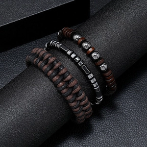 Three-piece men's bracelet set with braided leather and metal beads on a dark stand
