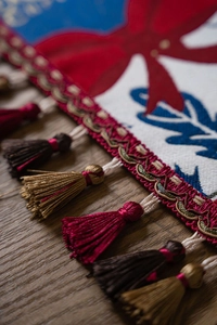 Close-up of jacquard table runner with decorative colorful tassels and embroidery detail