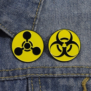 Biohazard and chemical symbol yellow enamel pins pinned on blue denim fabric background