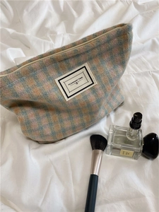 Detail of colorful plaid makeup bag with Pleasant Time label and zipper closure on soft fabric