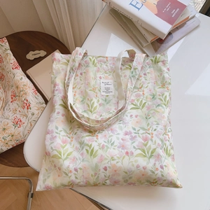 Détail d'un sac cabas en toile avec motifs floraux pastel et étiquette en tissu