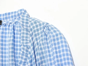 Detail view of blue and white gingham cotton shirt fabric with collar and seam stitching