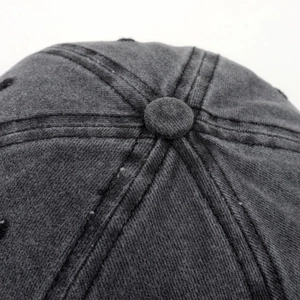 Gros plan du bouton supérieur et des coutures de la casquette en coton gris foncé