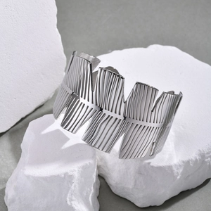 Detailed macro view of silver steel leaf pattern cuff bracelet on white stones