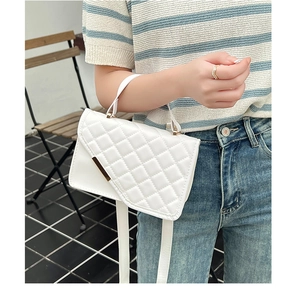 Detailed view of white quilted handbag with golden metallic bar and elegant handle