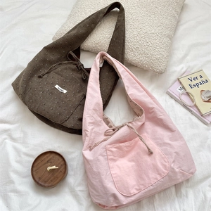 Detail of corduroy and cotton tote bags with front pockets on a cozy bed sheet