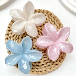 Three elegant marble texture flower hair claws in white pink and blue on a natural mat