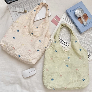 Détail de la texture gaufrée du sac fourre-tout avec broderie nœud et étiquette