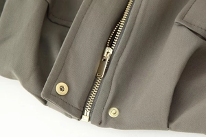 Detailed close-up of olive green jacket fabric with premium gold metal zipper and snaps