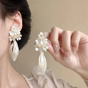 Detail of flower pearl earrings featuring white resin petals and teardrop pendants