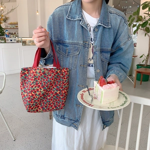 Close-up of floral corduroy tote bag featuring a vintage metal clasp and red handles