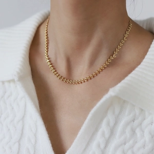 Elegant 18K gold plated wheat leaf choker necklace for women on a white knit sweater