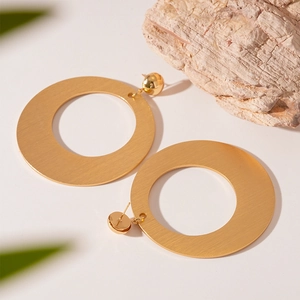 Detailed view of large golden geometric hoop earrings with brushed metallic texture