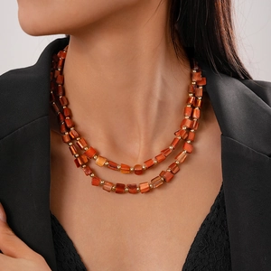 Detail of double-layer orange beaded necklace with irregular faux shell tiles on a model