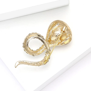 Detail of gold cobra snake brooch with intricate textures and a secure pin fastening