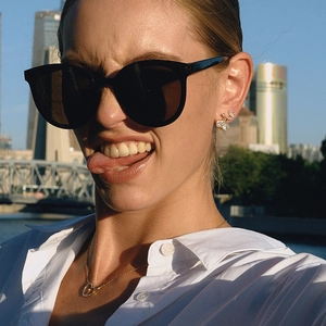 Golden butterfly earrings with zircons shown on model during golden hour city sunset