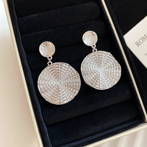 Detail shot of silver geometric round earrings with spiral texture on black velvet