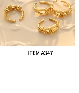 Macro shot of minimalist gold twist open rings on a cream-colored ceramic tray