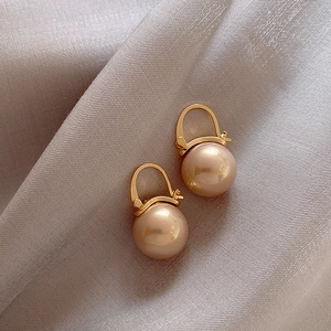 Elegant champagne pearl drop earrings with gold hooks on a gray silk satin background