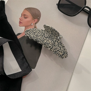 Detail of large acetate hair claw clip with beige and black spotted marble pattern
