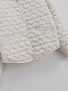 Detailed view of cream-white jacket featuring heart-shaped quilted stitching and buttons