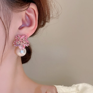 Close-up of pink crystal flower earrings with white pearls on a model ear