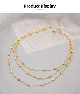 Close-up of golden triple-layered chain necklace with small polished metal beads