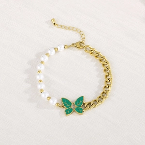Detailed macro view of green butterfly charm on pearl and gold Cuban chain bracelet