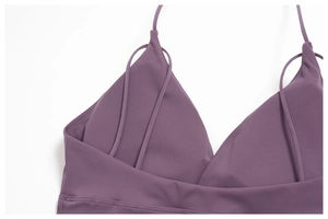 Detail of purple yoga top featuring slim straps and a criss-cross V-neckline design