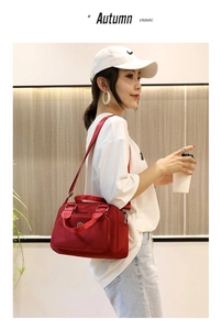 Detail of red nylon handbag featuring multiple zipper pockets and adjustable strap