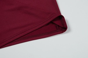 Close-up of double-needle hem stitching on wine red knitted dress fabric