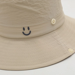 Close-up of beige quick-dry fabric bucket hat with black embroidered smiley face detail