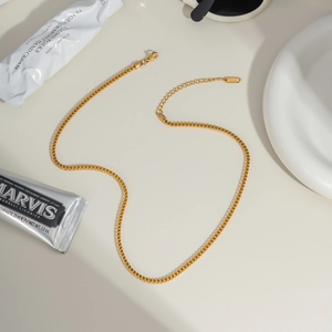Detail of golden stainless steel curb chain necklace with lobster clasp and extender