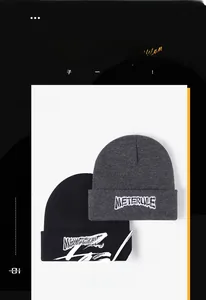 Détail de la broderie METERULE blanche sur des bonnets en maille épaisse noir et gris