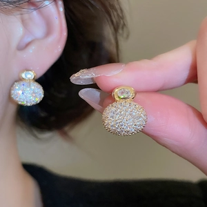 Close-up of gold plated stud earrings with micro-pave cubic zirconia on fingertips