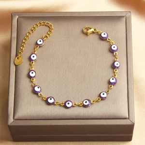 Detail of gold-plated stainless steel bracelet featuring purple enamel evil eye charms