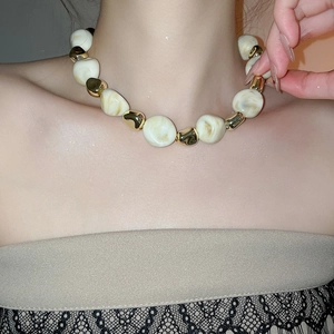 Close-up of beige acrylic marble beads and gold metallic spacers on a necklace