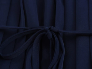 Detail of waist tie knot and fine pleated fabric on elegant navy satin dress