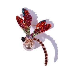 Luxurious dragonfly brooch with colorful rhinestones and a large pearl on a gold base