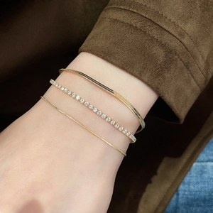 Detail of three-piece gold-plated bracelet set with snake chain and zircon tennis link