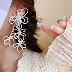 Detail of white beaded floral tassel earrings worn on model for an elegant look