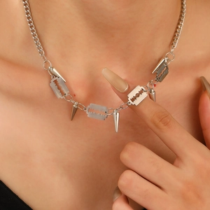 Punk silver necklace with razor blade and cone spike charms on a thick chain link
