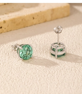 Macro detail of silver studs with round green faceted gems and secure butterfly clasp