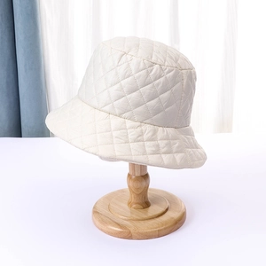 Close-up of quilted diamond pattern and glossy nylon texture on a cream bucket hat