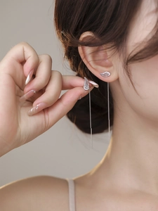 Detail showing long silver tassel wing earrings with sparkling crystals on a model