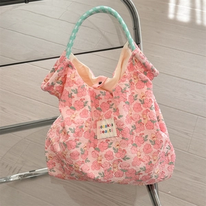 Detail of pink floral quilted handbag hanging on a chair with soft lighting
