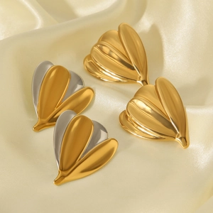Close-up of gold and silver flower earrings on elegant beige silk background