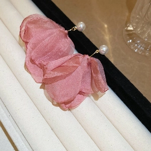 Detail shot of pink fabric flower petals and white pearl earrings on a white stand