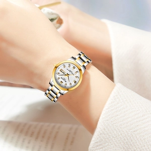 Classic silver and gold ladies watch with calendar dial worn on wrist in soft light